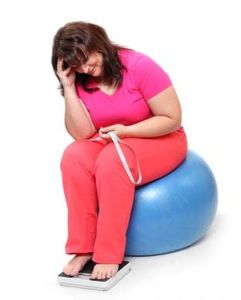 Overweight woman with a weighing machine and measure tape.